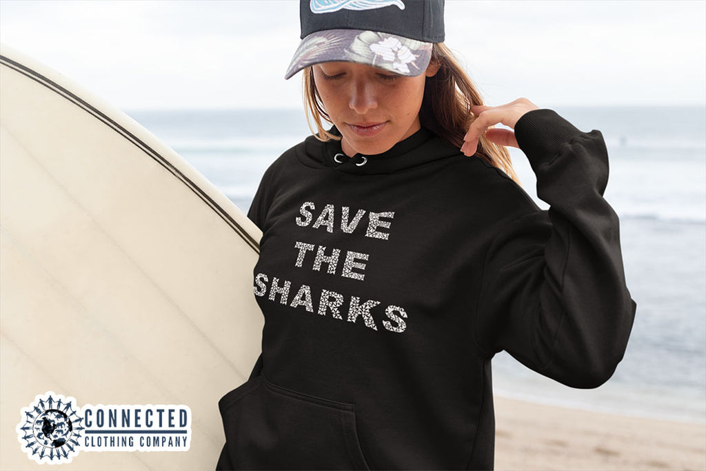 woman on the beach wearing black Save The Sharks Unisex Hoodie - sharonkornman - Ethically and Sustainably Made - 10% donated to Oceana shark conservation