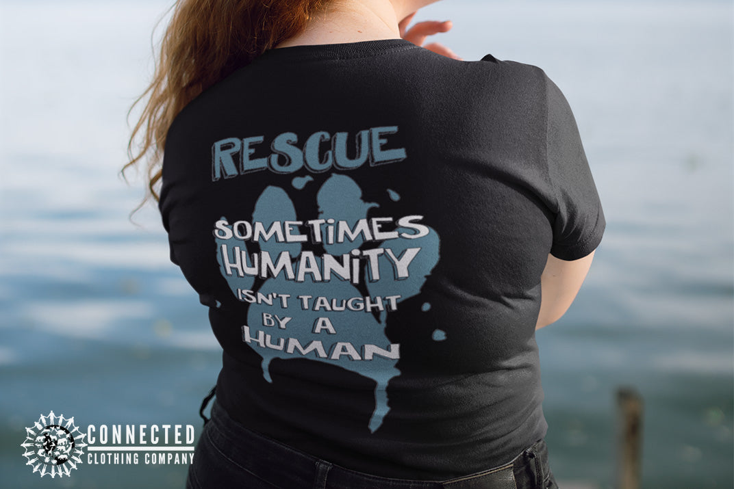 Model wearing Black Show Humanity Tee at the lake that reads "Rescue. Sometimes humanity isn't taught by a human" - sharonkornman - Ethically and Sustainably Made - 10% donated to the Society for the Prevention of Cruelty to Animals